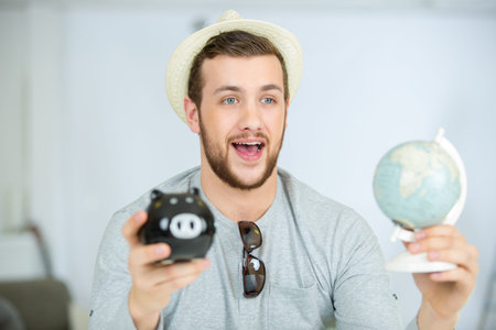 happy man holding piggy bank and globe