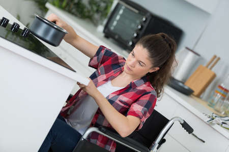 disabled woman in wheelchair preparing meal in kitchenの写真素材