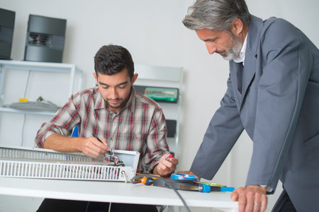 young man repairing applicance near mature male client
