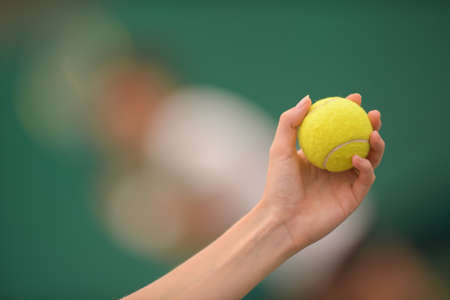tennis ball and hand on hard courtの写真素材