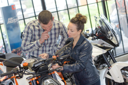 female selling motorbike to mature man in motorbike store