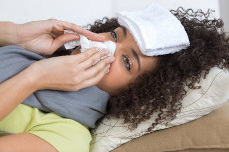 sick woman laying in bed sneezing