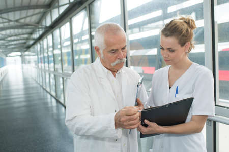 senior male doctor and nurse walking down corridorの写真素材