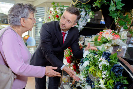 elderly woman buying flowers at funeral serviceの写真素材