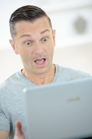 surprised man looking into computer screen