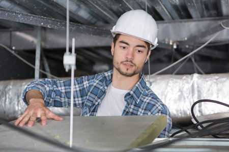 electrician fixes halogen lamp in ceiling light in room