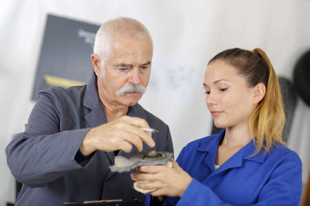 female apprentice using drill in factoryの写真素材