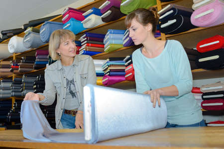 beautiful brunette choosing fabric skeins in textile shopの写真素材