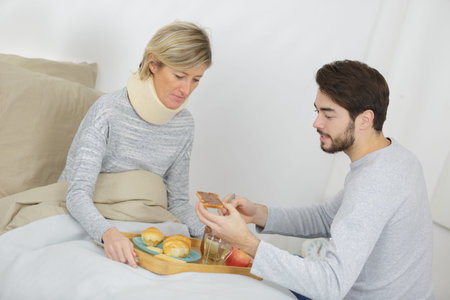son assisting ill mother lying in bedの写真素材