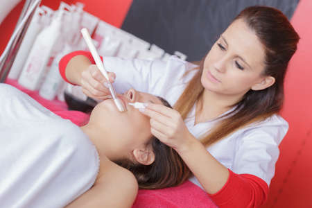 young woman lying with closed eyes having facial treatmentの写真素材