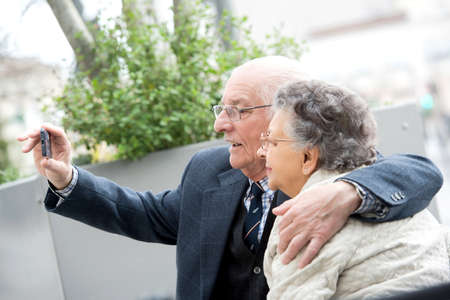 senior couple with camera taking selfie on streetの写真素材