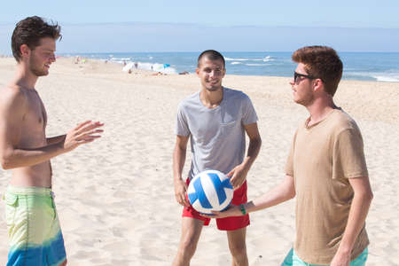 young men with volleyball playing volley on the beachの写真素材