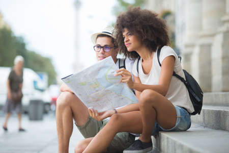 Couple sitting in a monument sightseeing sharing a mapの写真素材