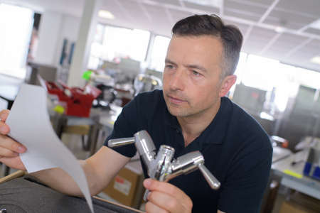 male plumber working on sink reading instructionsの写真素材