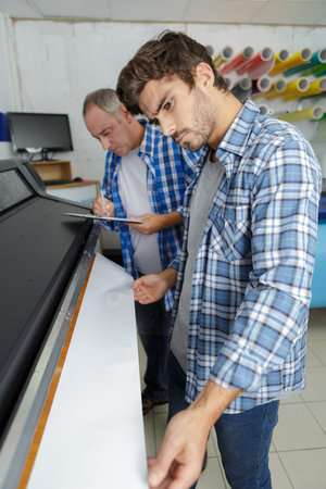 man pushing huge roll of paper in newspaper factory