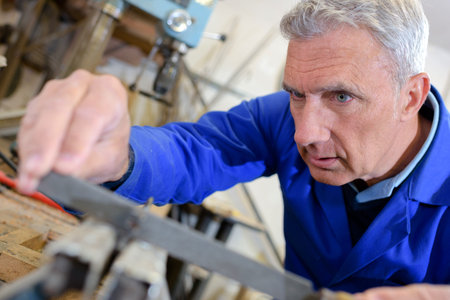senior worker operates metalworking machine