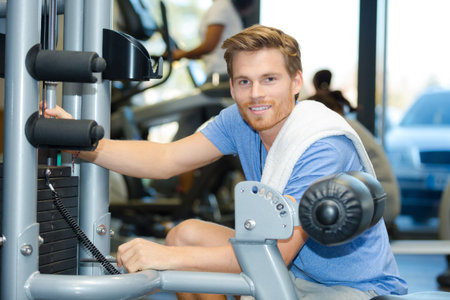 smiling young man using fly machine in gym