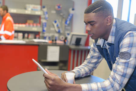 young man using his digital tablet on a coffee breakの写真素材