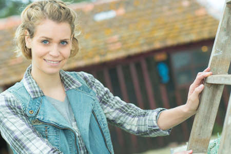 happy woman ready to use a ladder outsideの写真素材