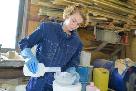 female worker making fiberglass to fix a boat in workshopの写真素材