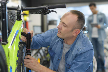 man checks bike before buying in sports shopの写真素材