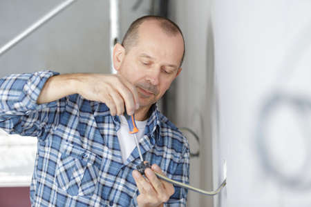 middle-age male electrician wiring a new buildの写真素材