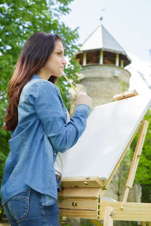 young woman draws on an easel outdoorsの写真素材