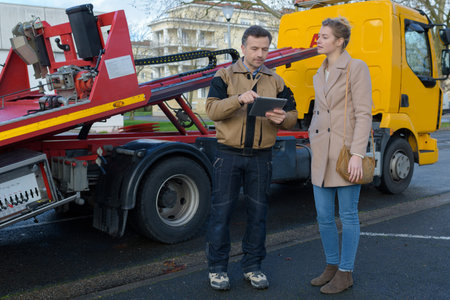 car assistance technician checking auto and writing on clipboardの写真素材