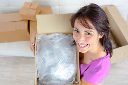 smiling young woman opening a carton boxの写真素材