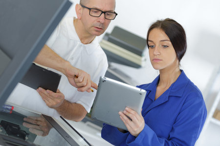 young female mechanic using a tablet with manager