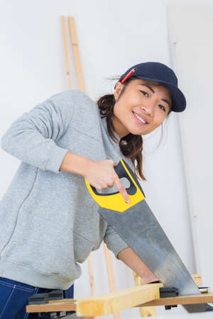 girl is sawing a wooden beam the hand sawの写真素材