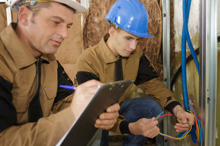 teacher observing student working on electrical circuitsの写真素材