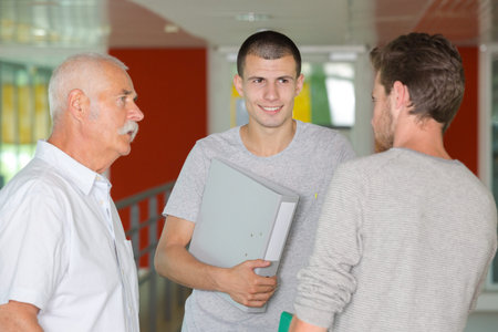teacher and teenage boys talking on the corridorの写真素材