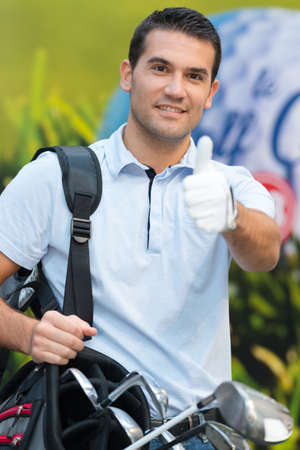 smiling golfer man showing thumbs up while standing on fieldの写真素材