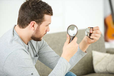 astonished man looking through a magnifying glassの写真素材