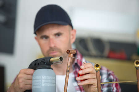 plumber welding copper and fittings with blowtorchの写真素材