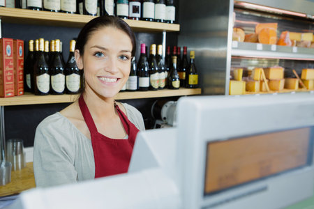 beautiful female food store employee at the cashier smiling
