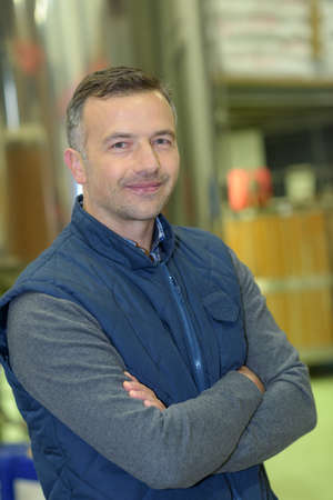 warehouse worker smiling at camera with arms crossedの写真素材