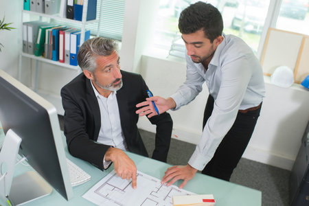 two architects discussing blueprints in the office