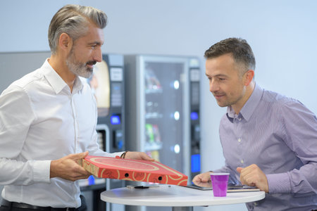 two colleagues having a pizza during lunchbreak at the office