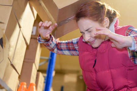 carton falling on womans head at the factoryの写真素材