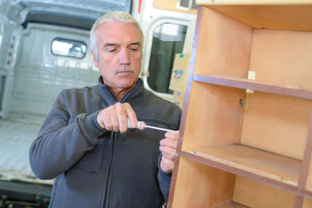 mover disassembling cabinet to fit into truckの写真素材