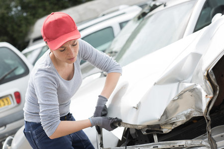 Scrapyard worker with accident damaged car