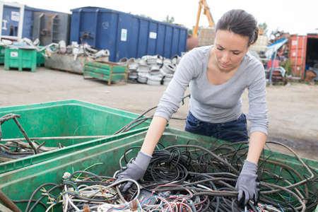 Woman at container of cables in salvage yardの写真素材