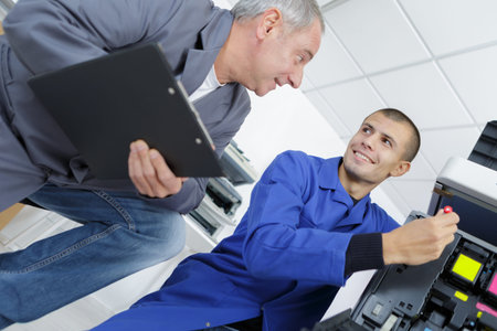 Young man learning to repair photocopier
