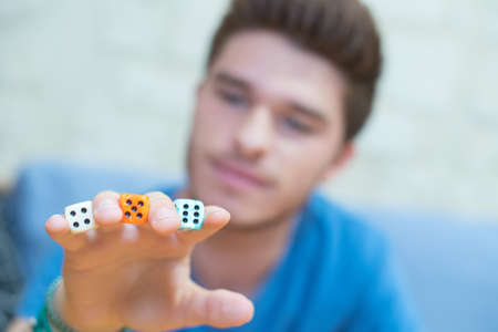 Young man with dice between his fingersの写真素材