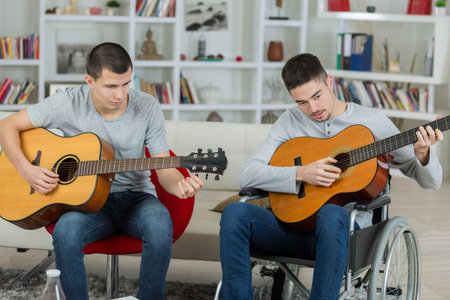 Two young men playing guitars, one in a wheelchair