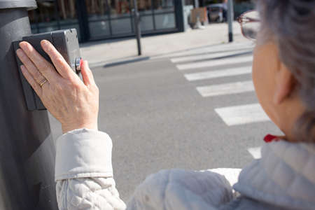 Elderly lady pushing button at pedestrian crossingの写真素材