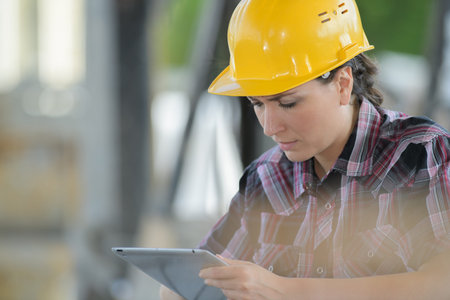 Woman wearing hardhat looking at tablet