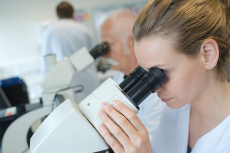 Laboratory worker looking into microscope eyepieceの写真素材